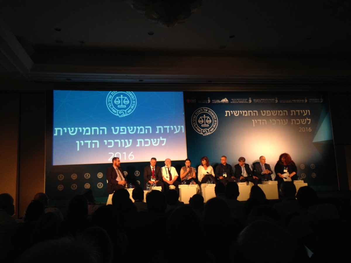 פאנל של 9 דוברים רשמיים מול קהל חי. ברקע הכיתוב "ועידת המשפט החמישית לשכת עורכי הדין 2016"